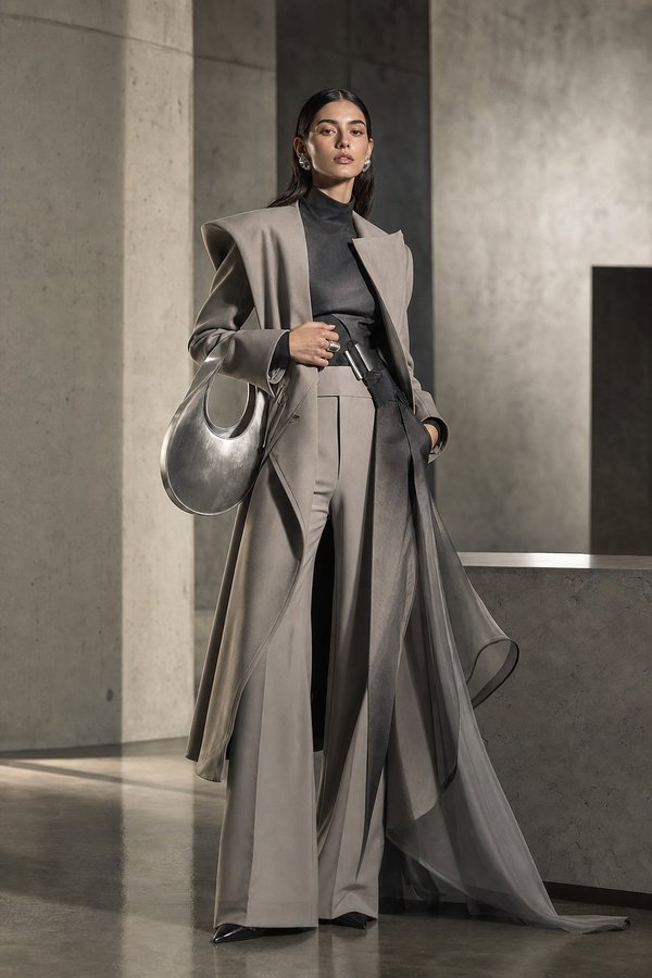 Cloud-generated fashion photograph: long taupe layered coat in a concrete gallery